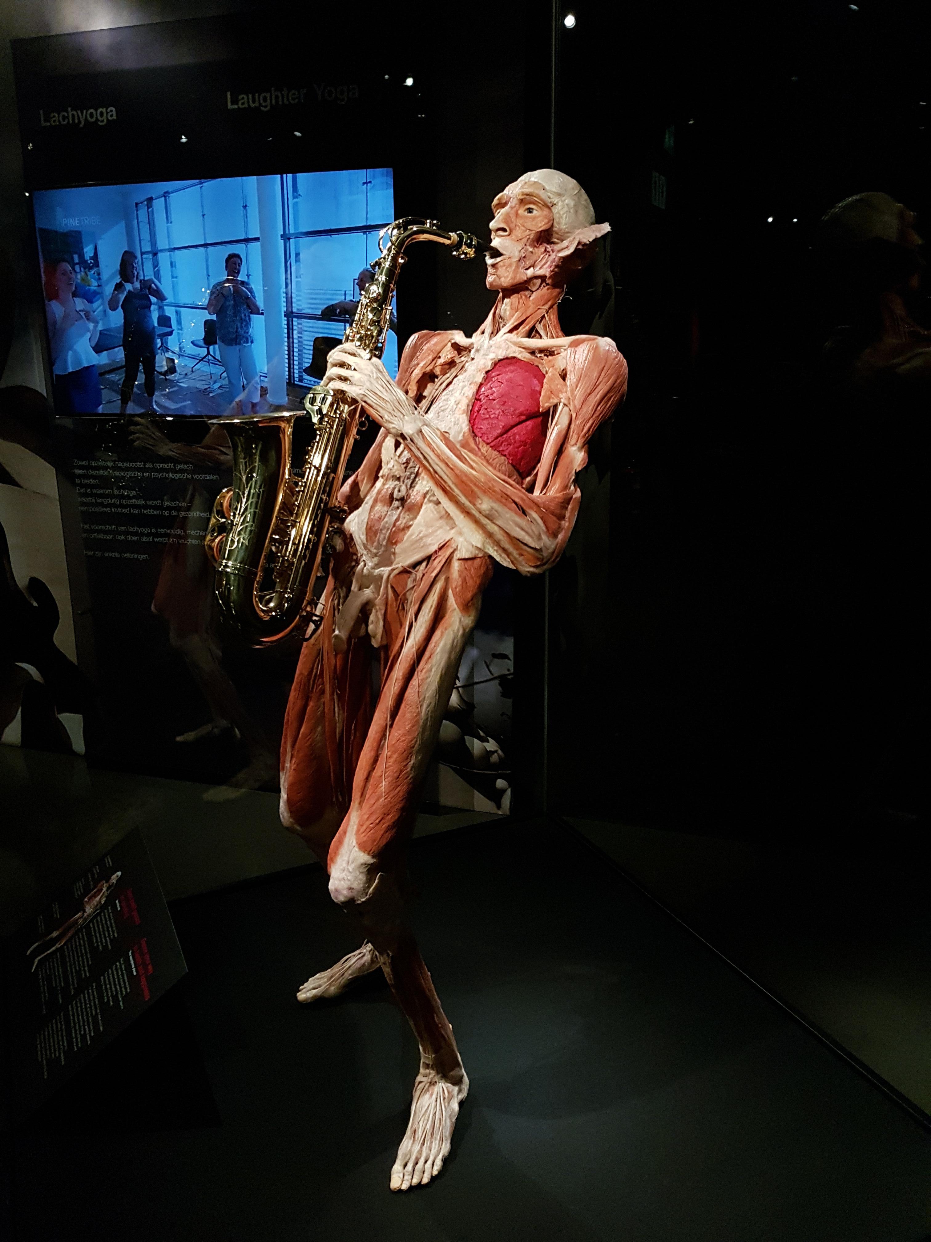 A statue of a man without skin and fat playing a saxophone