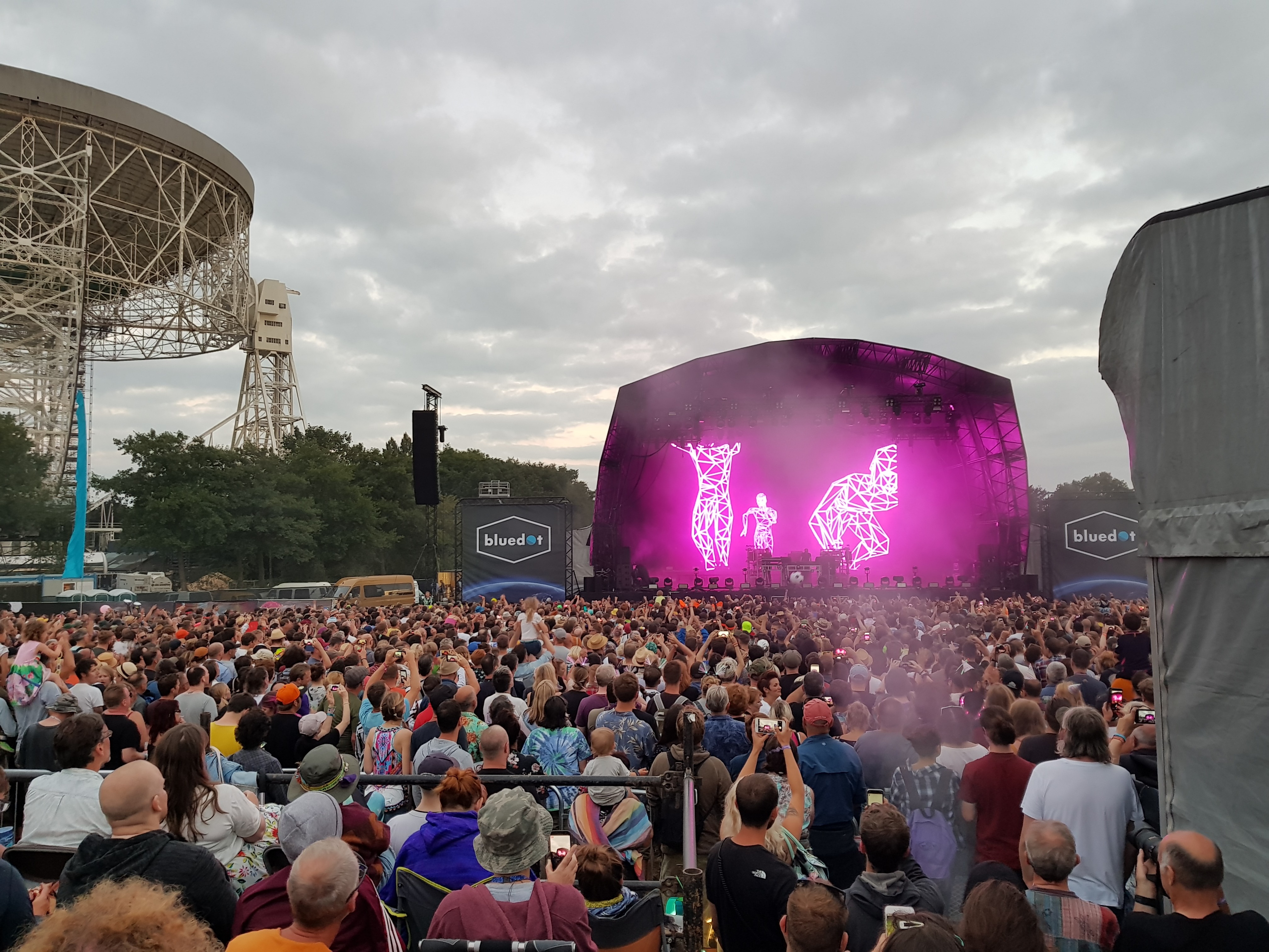 A large crowd is standing in front of a stage watching the chemical Brothers perform.