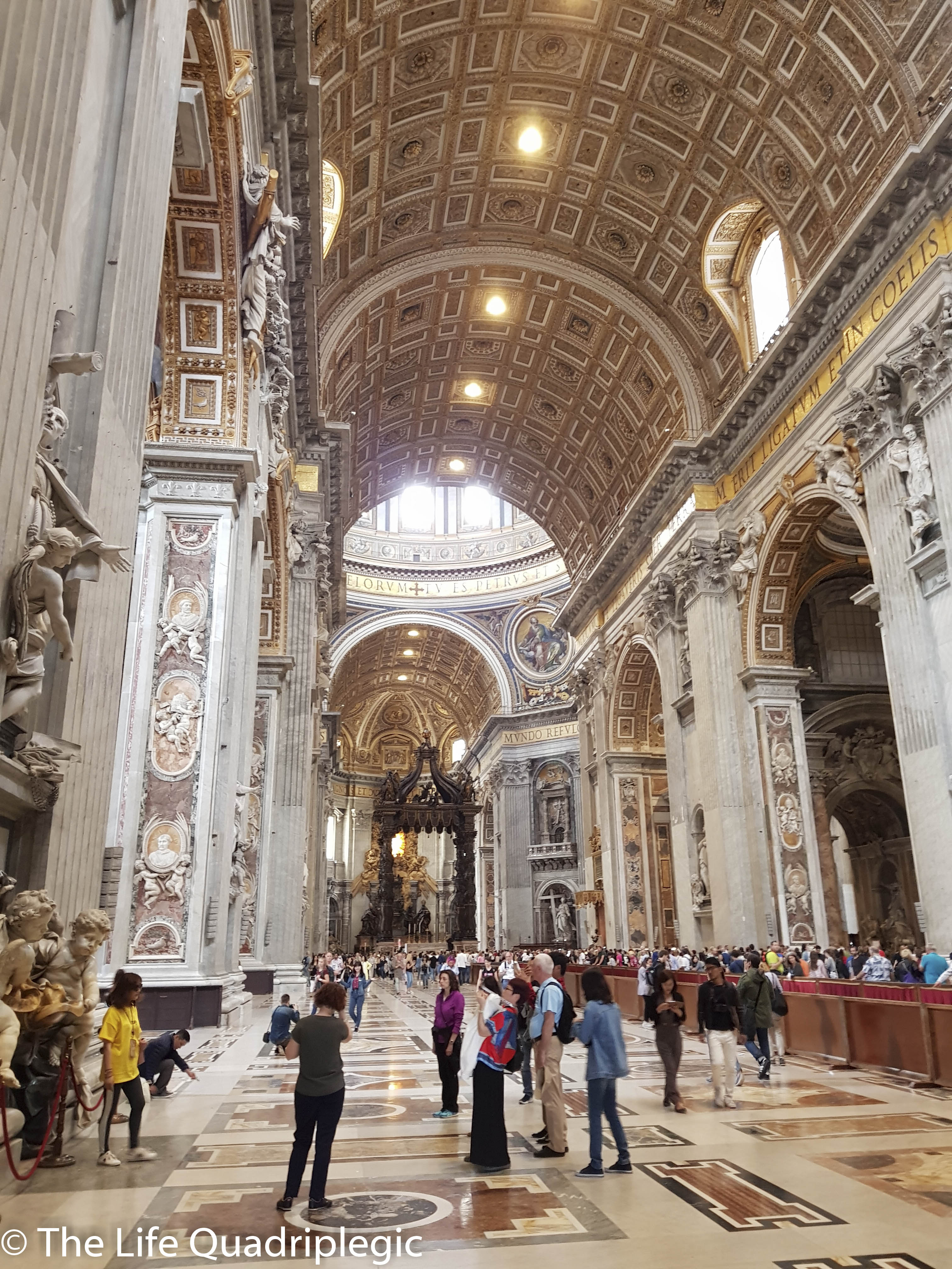 Interior view of St. Peter's Basilica in Vatican City, showcasing ornate architecture, high ceilings, and crowds of visitors.