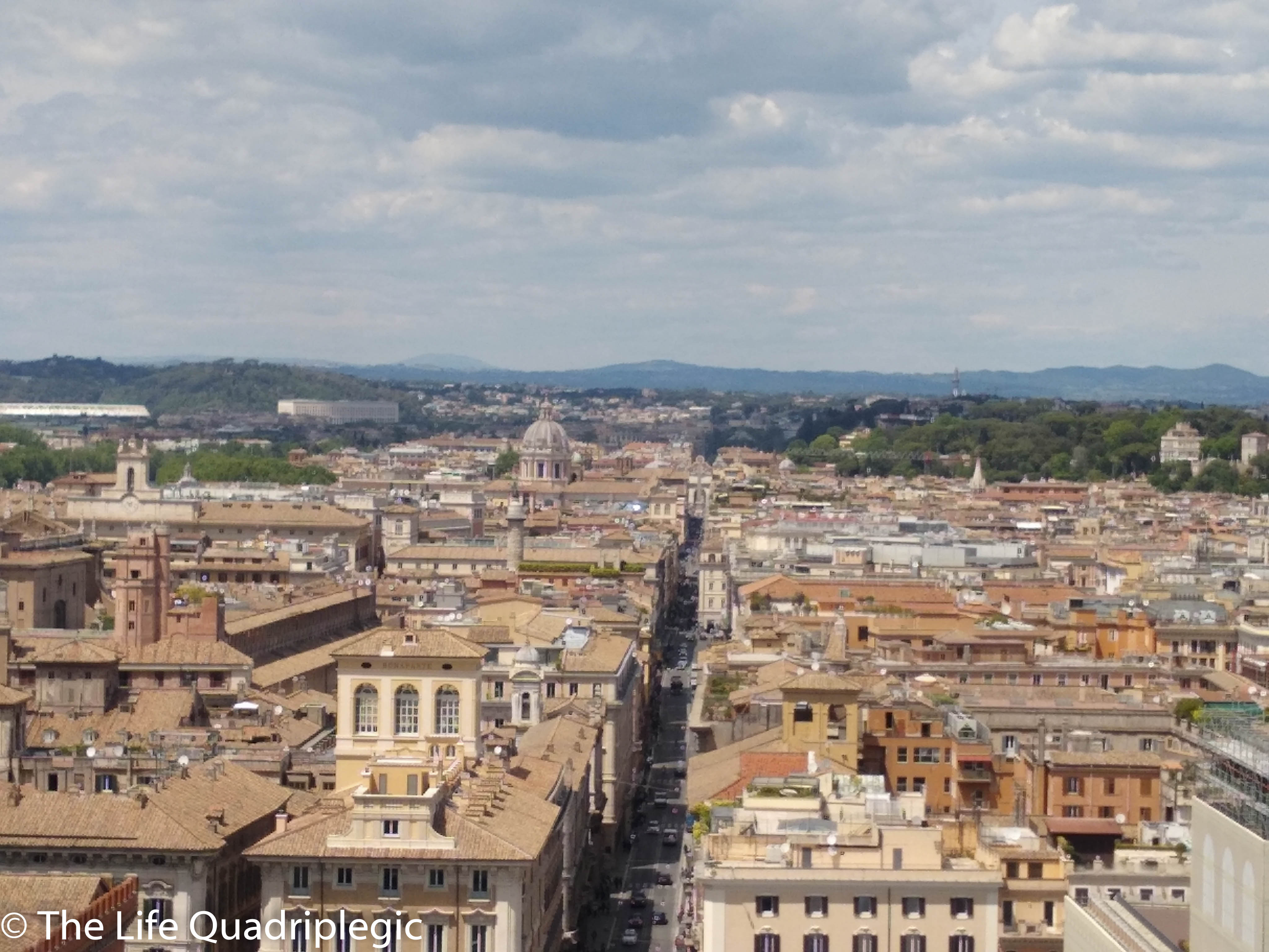 A panoramic view of Rome showcasing its historic architecture, terracotta rooftops, and landmarks under a partly cloudy sky.