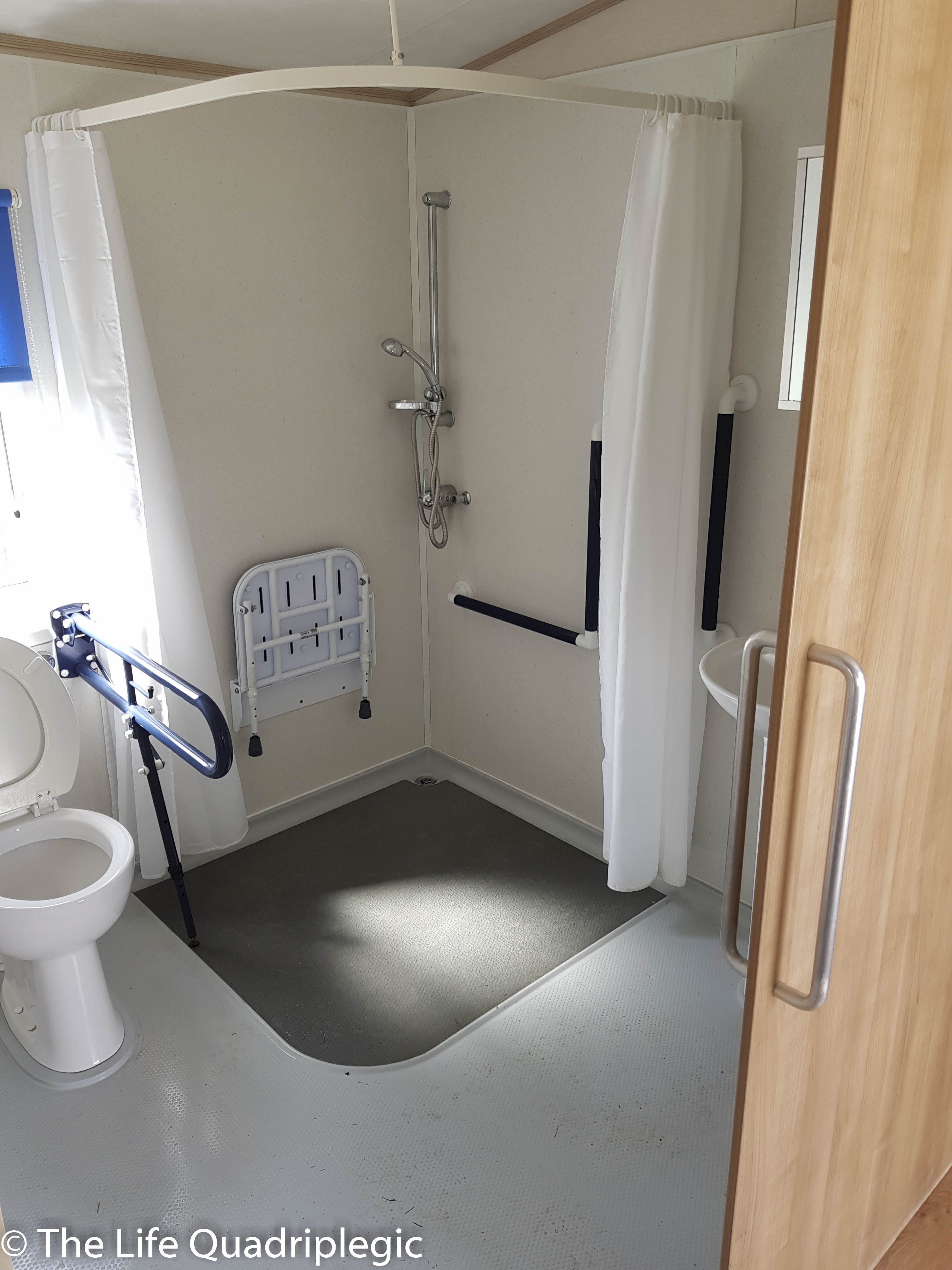 Accessible bathroom featuring a roll-in shower, grab bars, and space for wheelchair maneuverability.