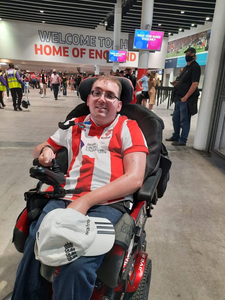 Me sitting in my wheelchair wearing a football top on the concourse inside Wembley stadium