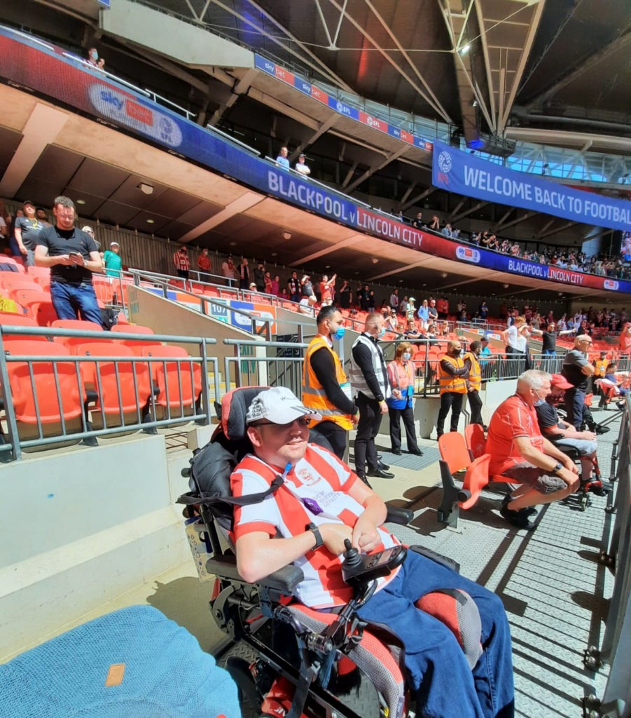 Me sat in a wheelchair space with stewards stood a short distance behind me