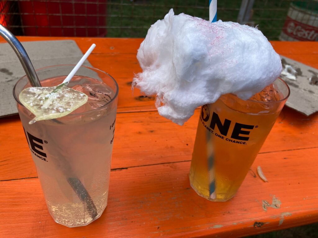 2 glasses of cocktails, one with a lollipop lying across the top and the other with a large amount of candy floss on top of it