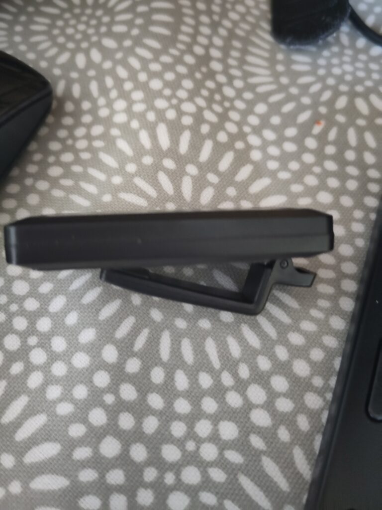 A sideways view of a small thin black plastic device with a clip on the back