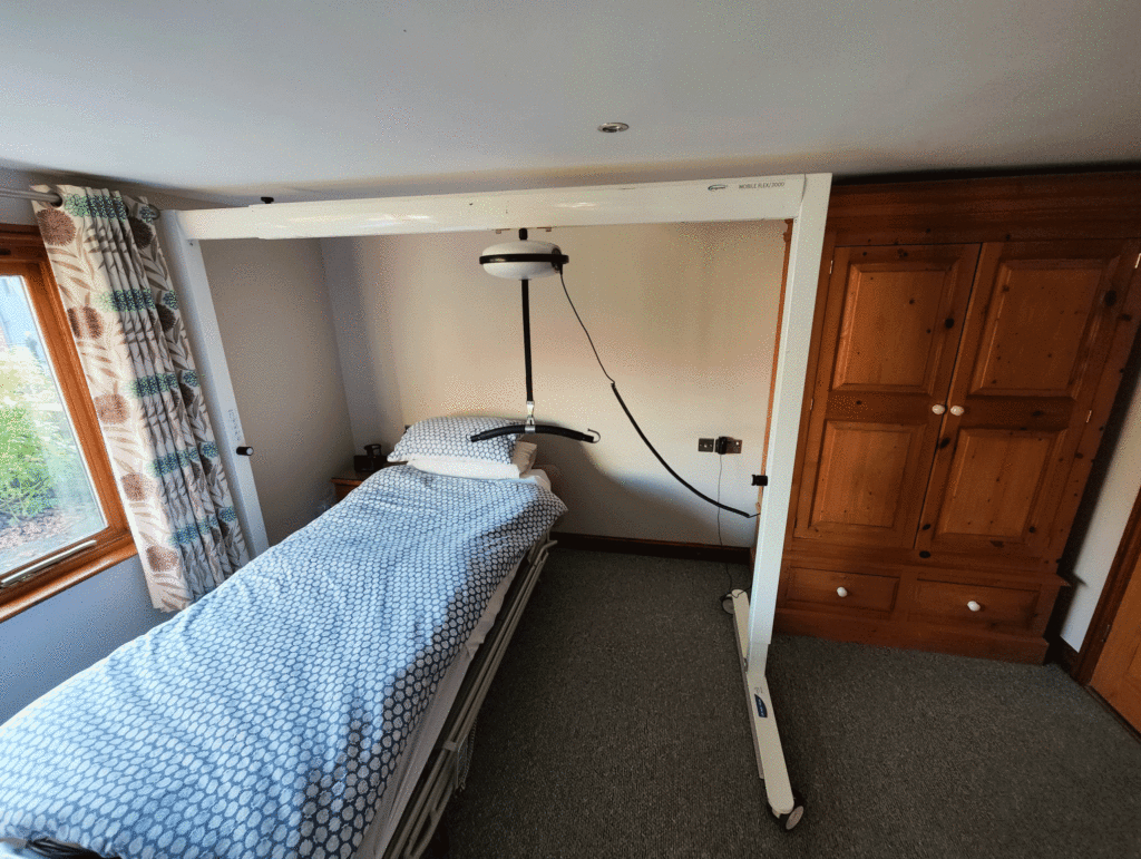 a bed in a room with a metal frame over the bed and a hoist attached to the top horizontal bar of it.