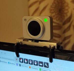 Close-up view of the Silver metal HeadMouse Nano camera mounted on a computer monitor, with a green indicator light visible.