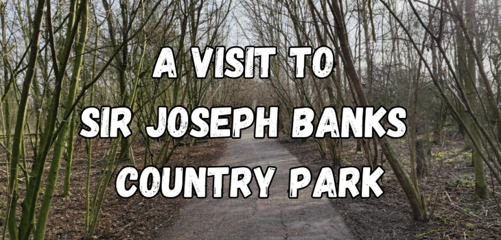 A paved path winds through leafless trees in Joseph Banks Country Park, with bold white text over the image reading “A Visit to Sir Joseph Banks Country Park.”.