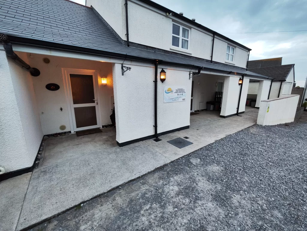 Exterior view of Clementine Cottage, an accessible holiday home in Port Eynon, Wales, showcasing the front entrance and parking area.