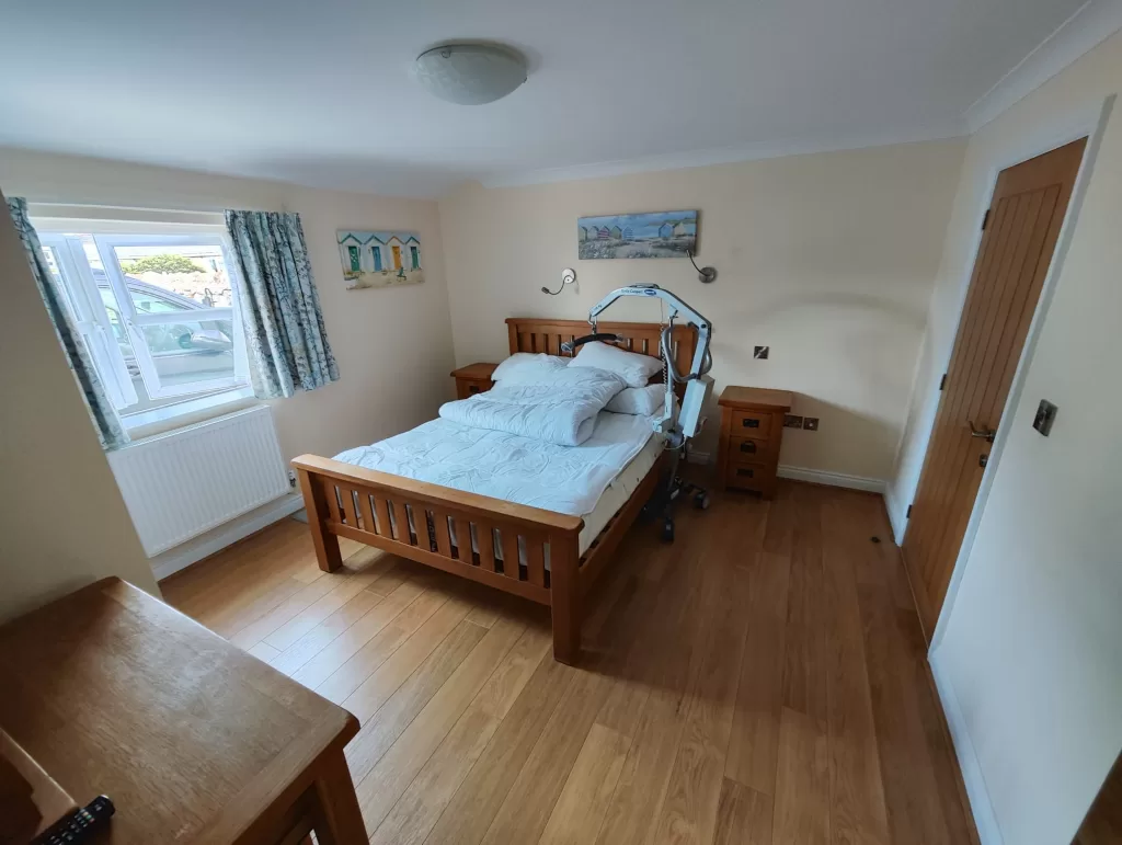 An accessible bedroom in a holiday cottage featuring a double bed, bedside tables, and a mobile hoist.