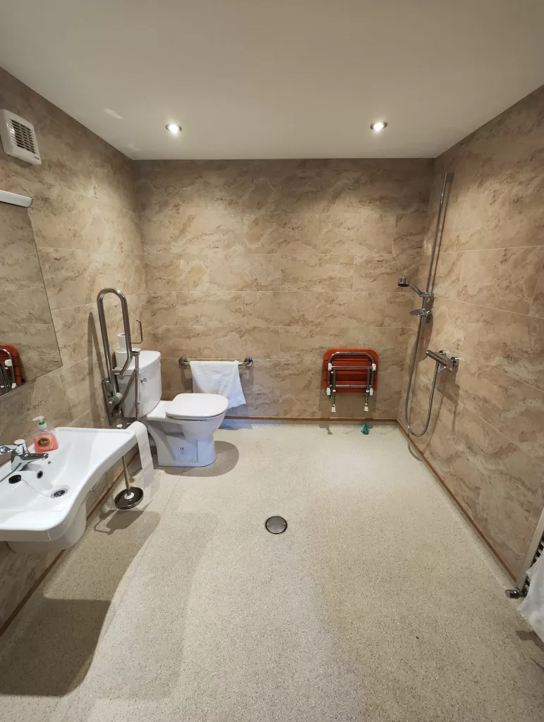 Accessible bathroom in Clementine Cottage featuring a wheel-in shower, grab bars, and a large sink suitable for wheelchair users.