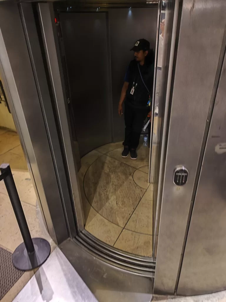 An accessible elevator with a staff member inside, featuring sleek metal doors and a minimalistic design.