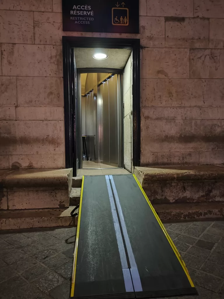 An accessible entrance featuring a ramp leading to a lift, marked with a sign indicating restricted access.
