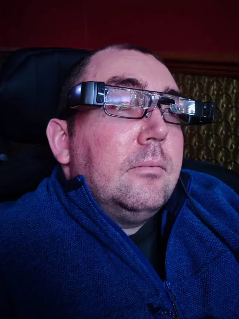 A person wearing WatchWord subtitle glasses while seated in a cinema, looking towards the screen.
