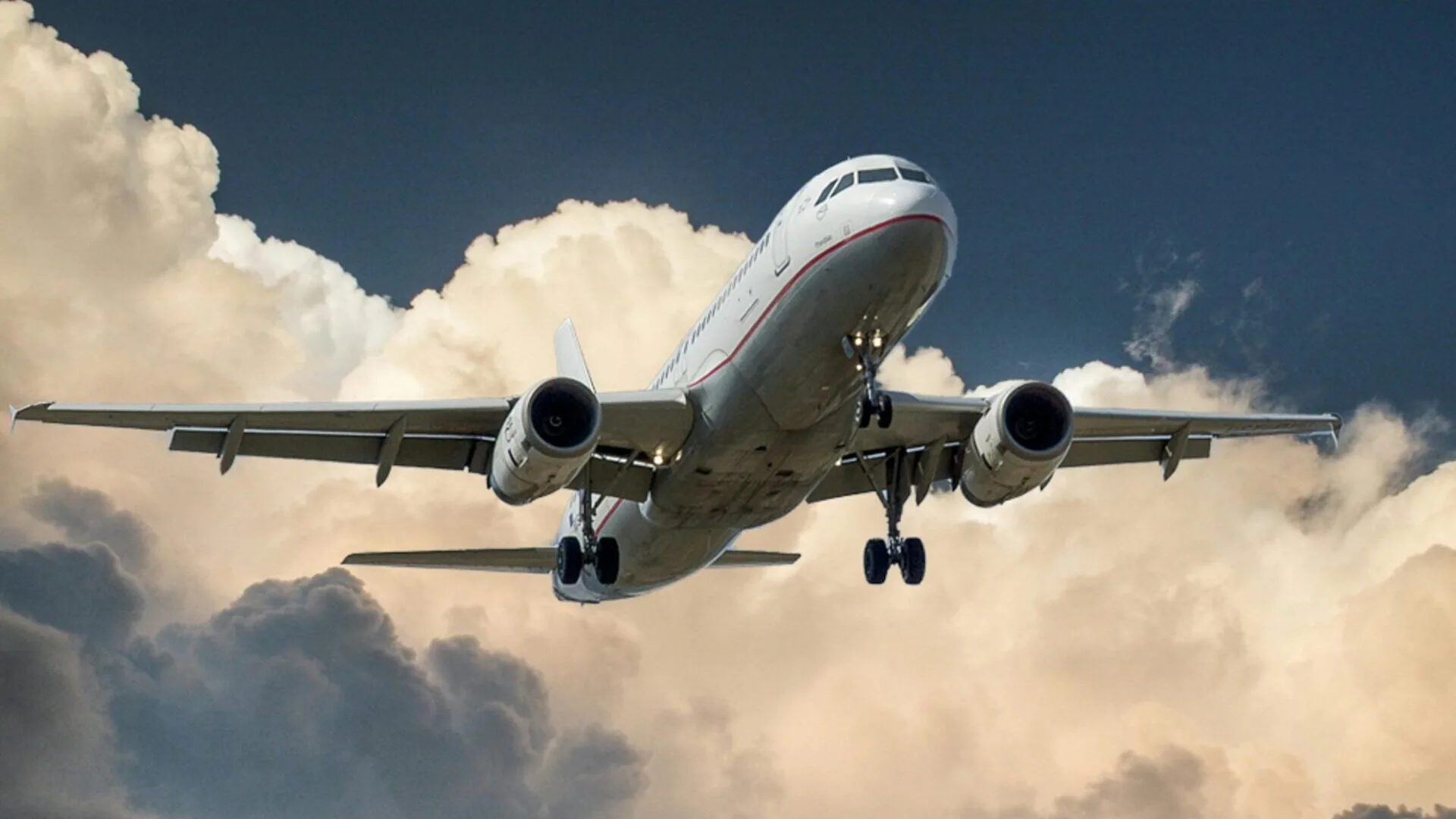 A passenger jet  in flight with clouds in the background